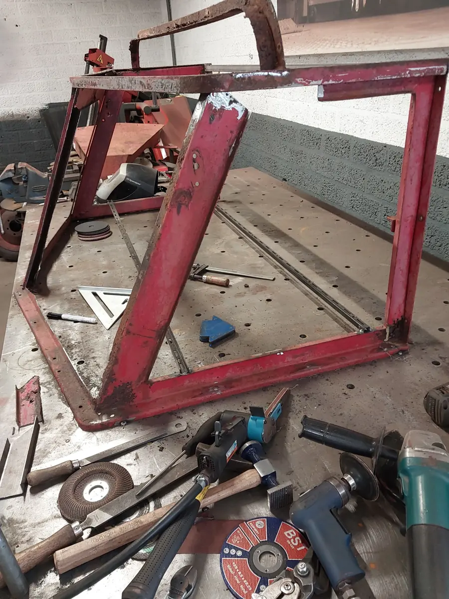Het kale, roestige frame van de Snow-Trac op de werkbank, tussen het gereedschap