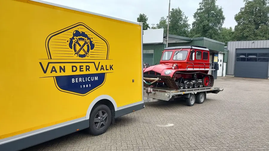 De Snow-Trac op een aanhanger achter de gele Van der Valk-bus